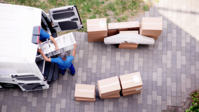 Männer heben Möbel und Kisten in einen Transporter.